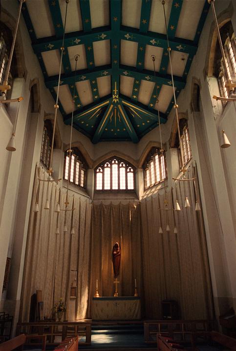 The interior of a cathedral features a high, decorated ceiling, stained glass windows, and an altar with a statue.