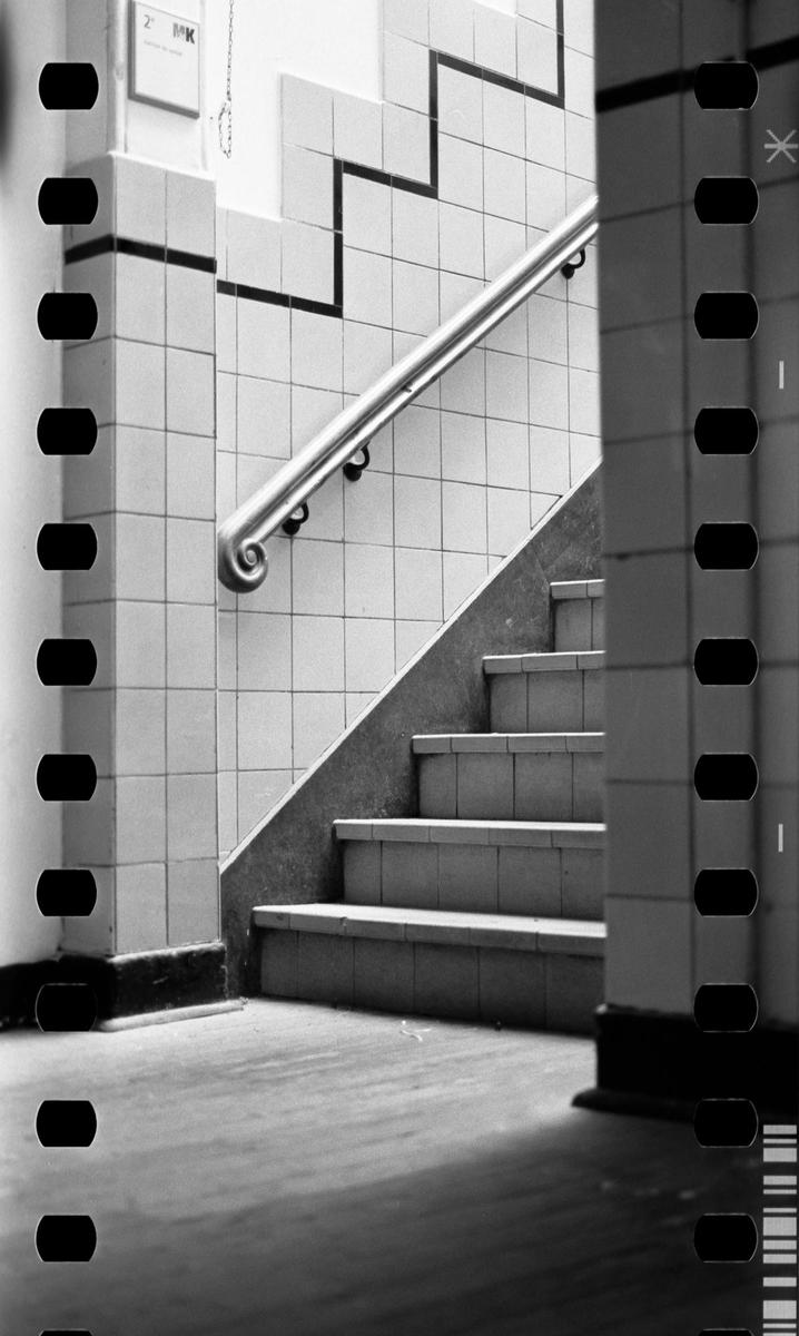 A tiled staircase with a handrail ascends from the bottom right to the top left of the frame.
