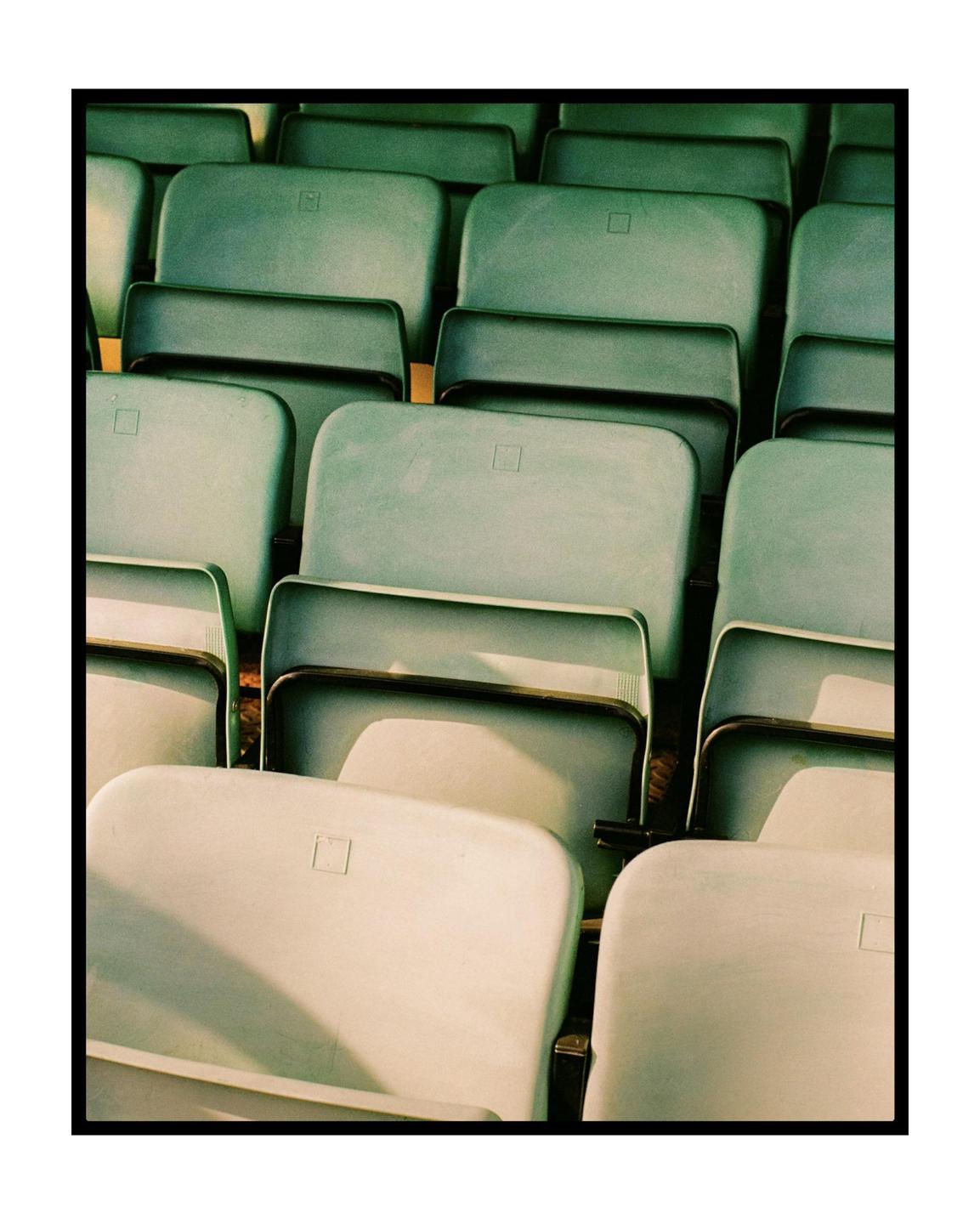A grid of empty stadium seats in varying shades of green and white is shown.