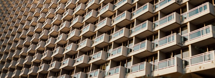 A building with many balconies is shown from a low angle.