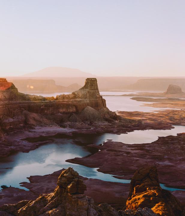 A vast landscape of rock formations and water is illuminated by the rising sun.
