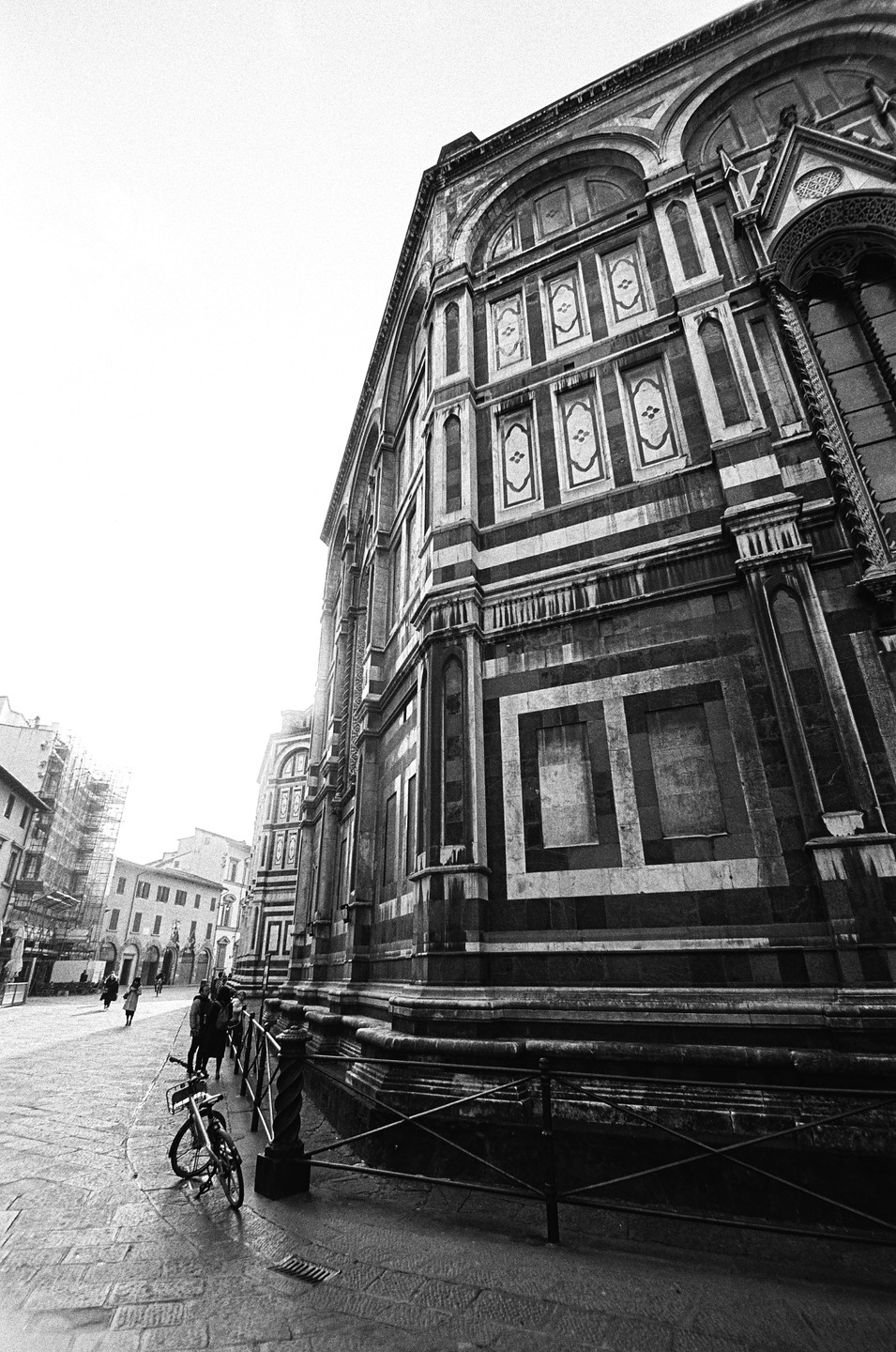 A bicycle is parked next to a fence in front of a large, ornate building with striped patterns.