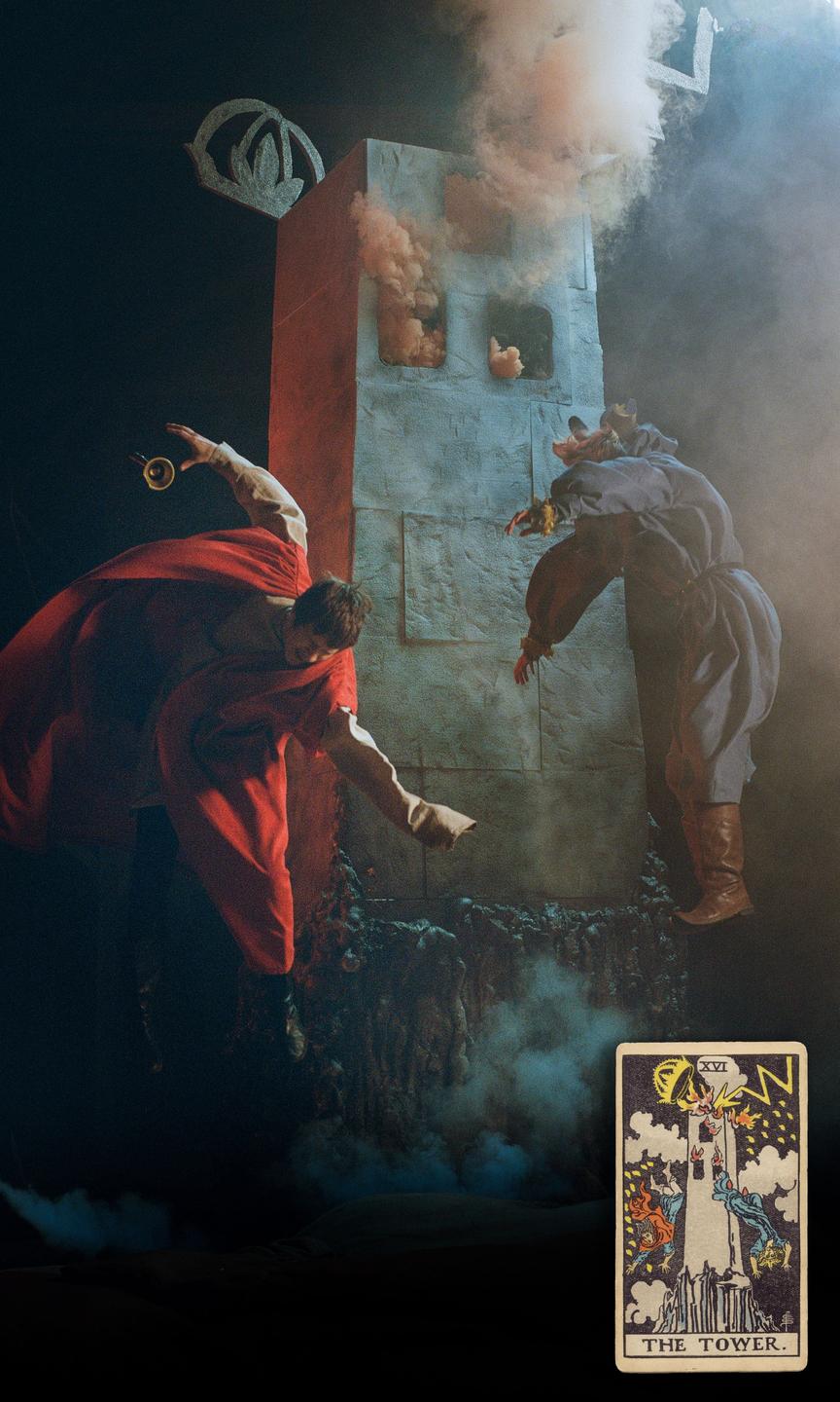 Two people in elaborate costumes fall from a burning tower, with a tarot card depicting a similar scene in the bottom right corner.
