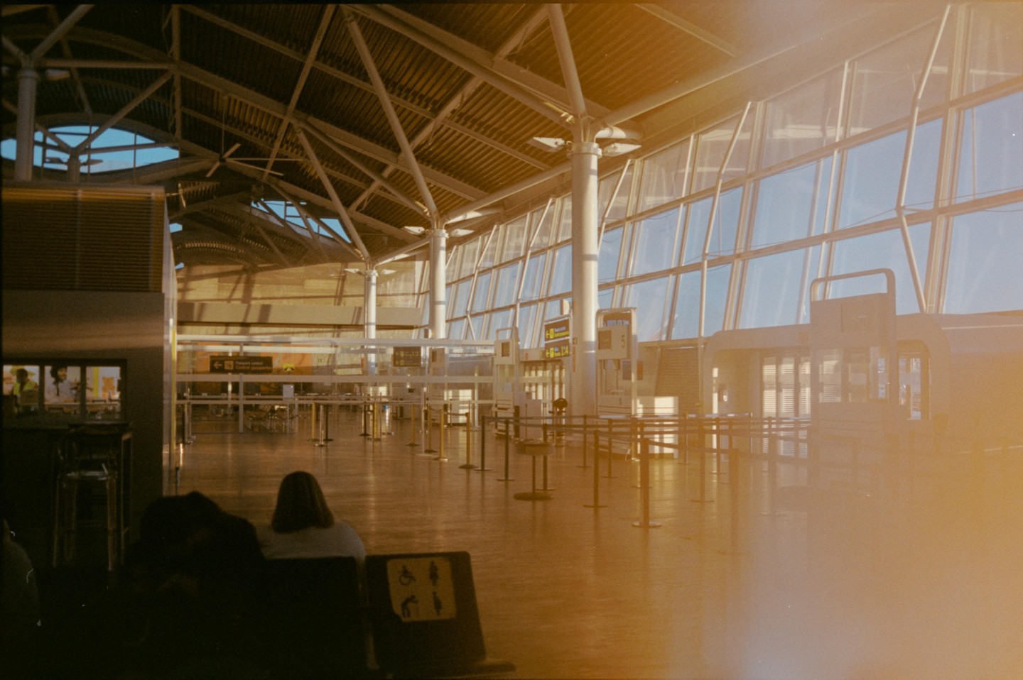 A woman sits in an airport terminal with large windows and a high ceiling.