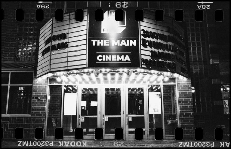 The Main Cinema is illuminated at night, with its marquee and entrance visible.