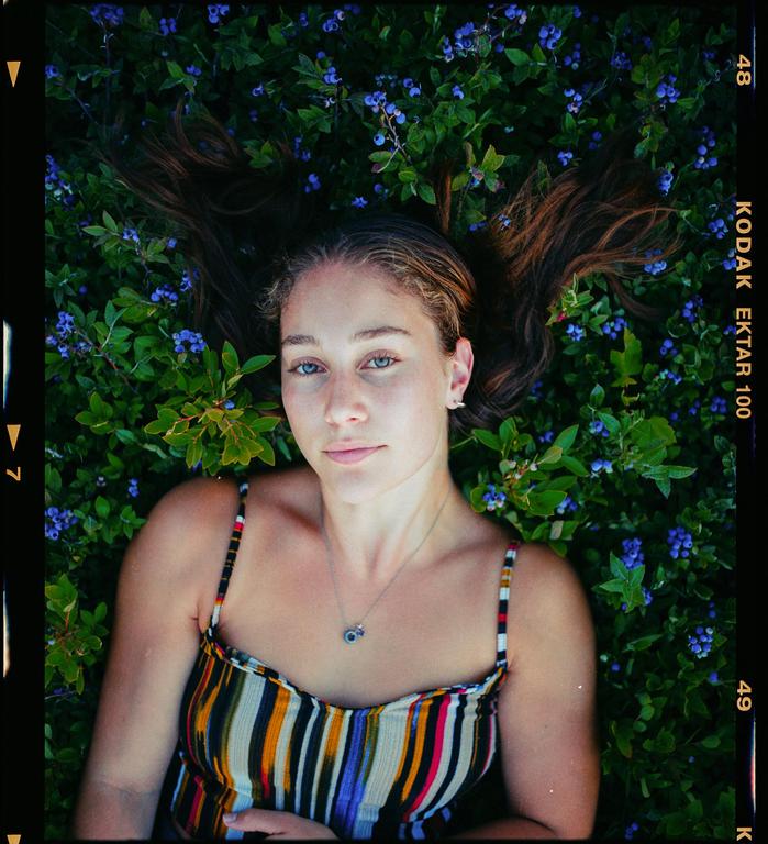 A woman with long hair lies in a field of blueberries.