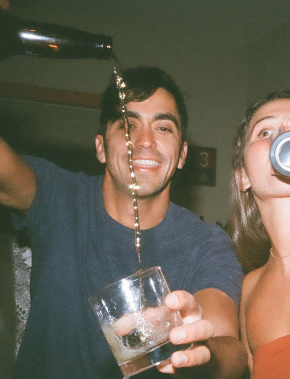 A man pours a drink into a glass while a woman drinks from a can.