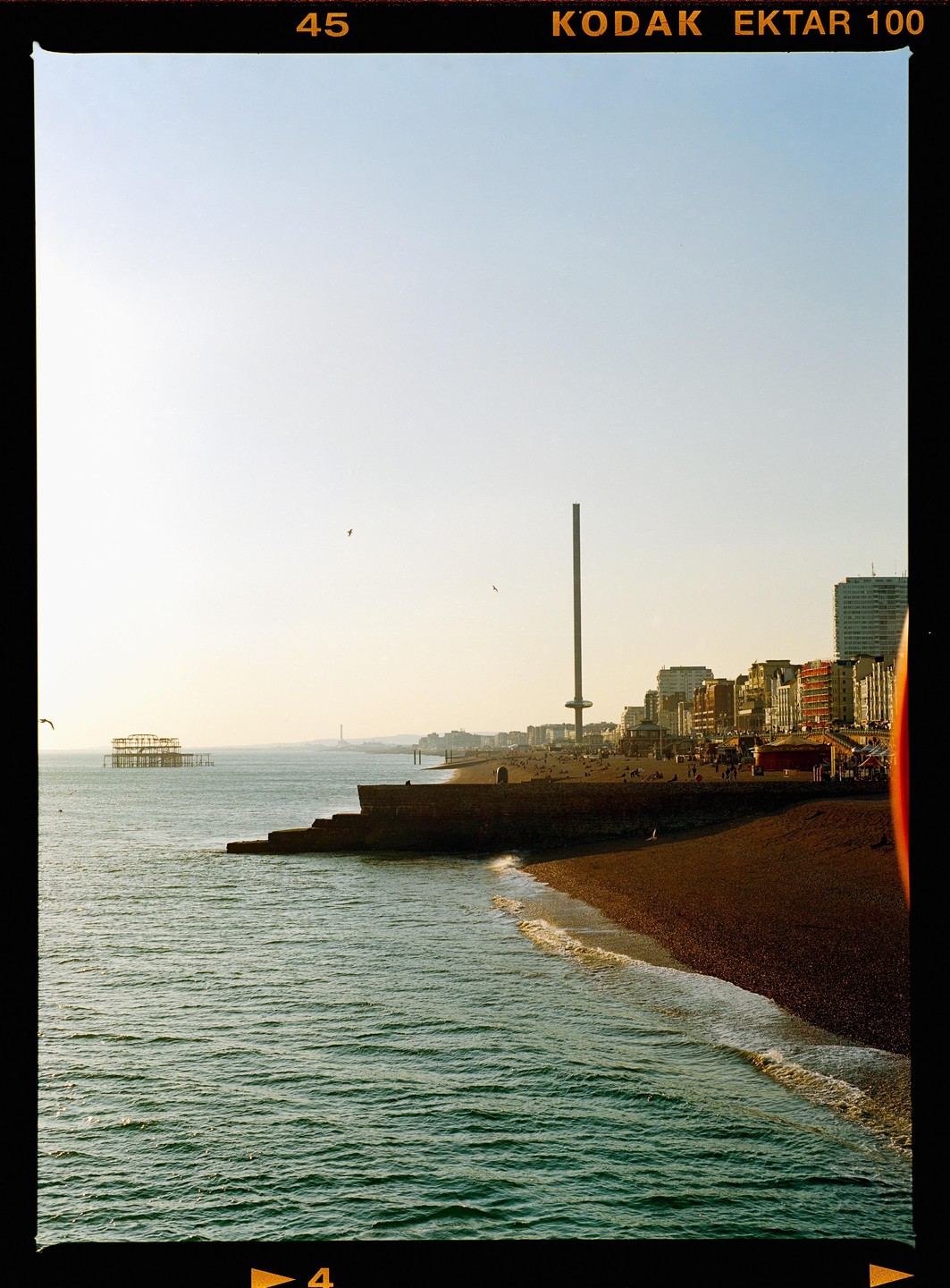 A beach with a pier and a tall tower is visible under a clear sky.