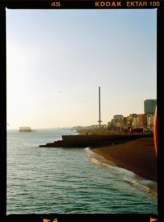 A beach with a pier and a tall tower is visible under a clear sky.