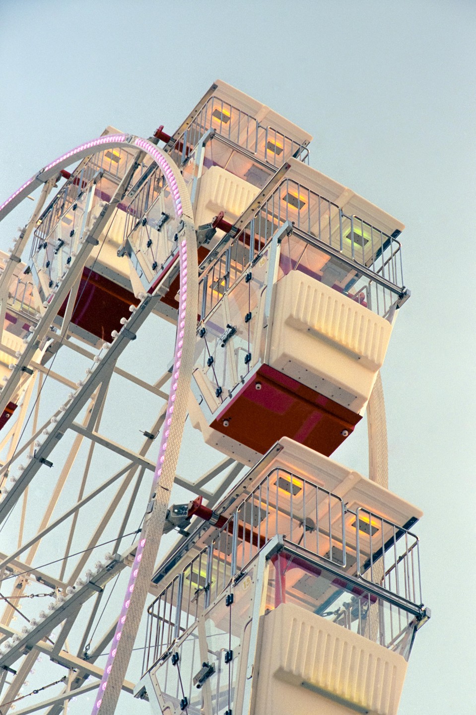 A ferris wheel with empty gondolas is shown against a clear sky.