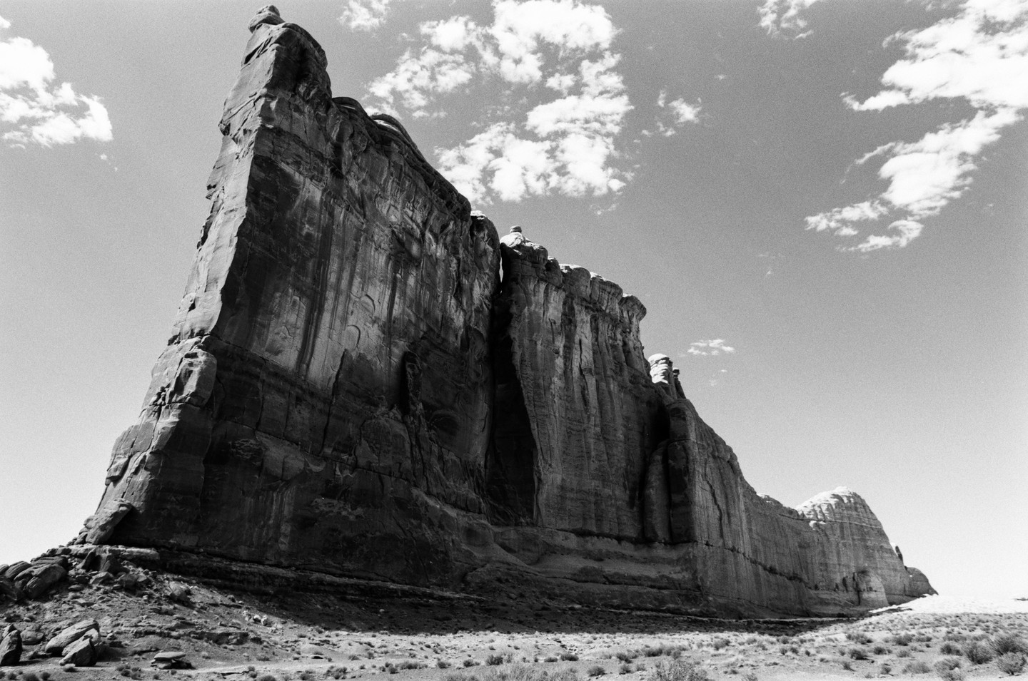 A large rock formation stands tall against a sky with scattered clouds.