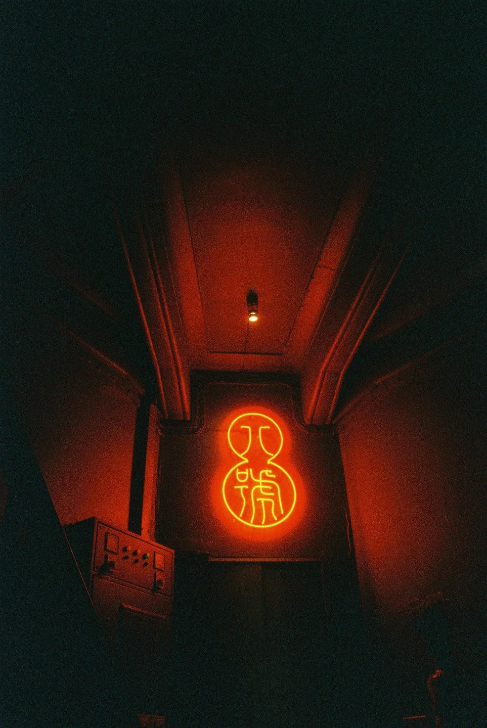 A neon sign with Chinese characters glows orange on a dark wall.