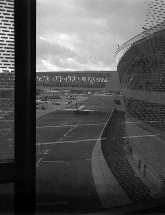 An airplane is parked on the tarmac next to a modern airport terminal building.