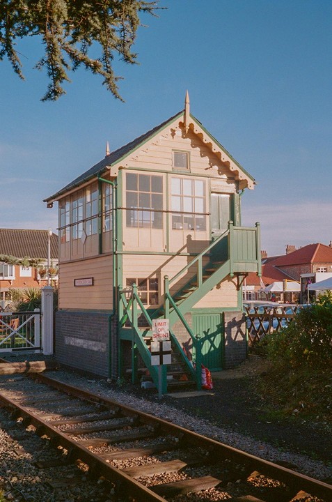 A signal box with green stairs and a sign that reads "Limit of Shunt" stands next to a railway track.