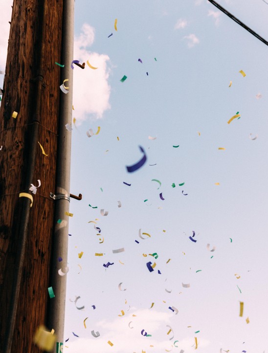 Colorful confetti falls through the sky next to a wooden utility pole.