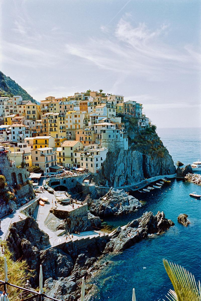 A village with colorful buildings is built into a cliff overlooking the sea.