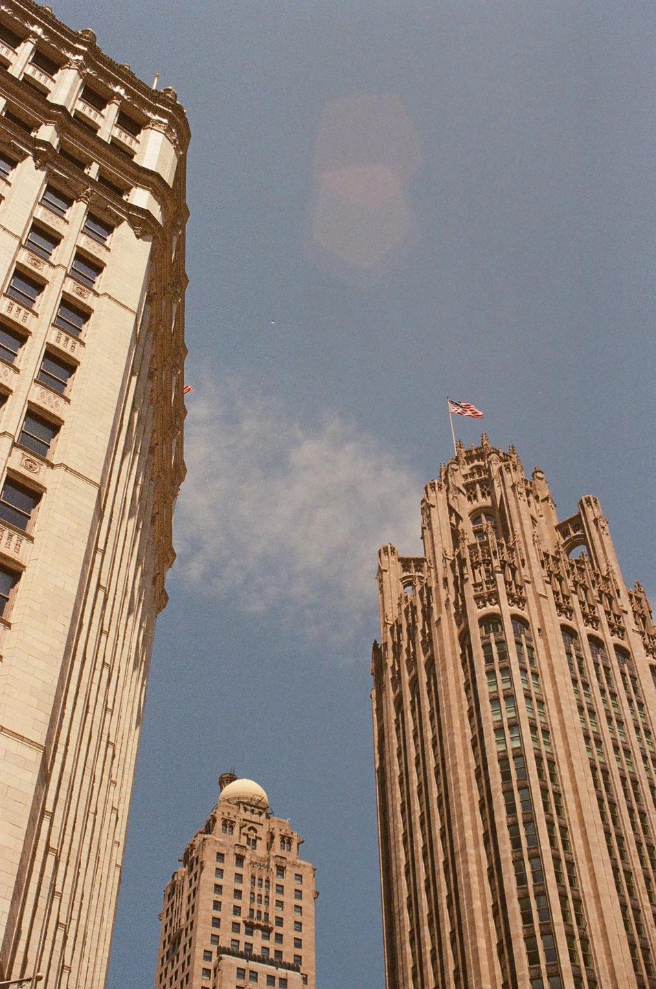 Three tall buildings are visible from a low angle against a blue sky with a few clouds.