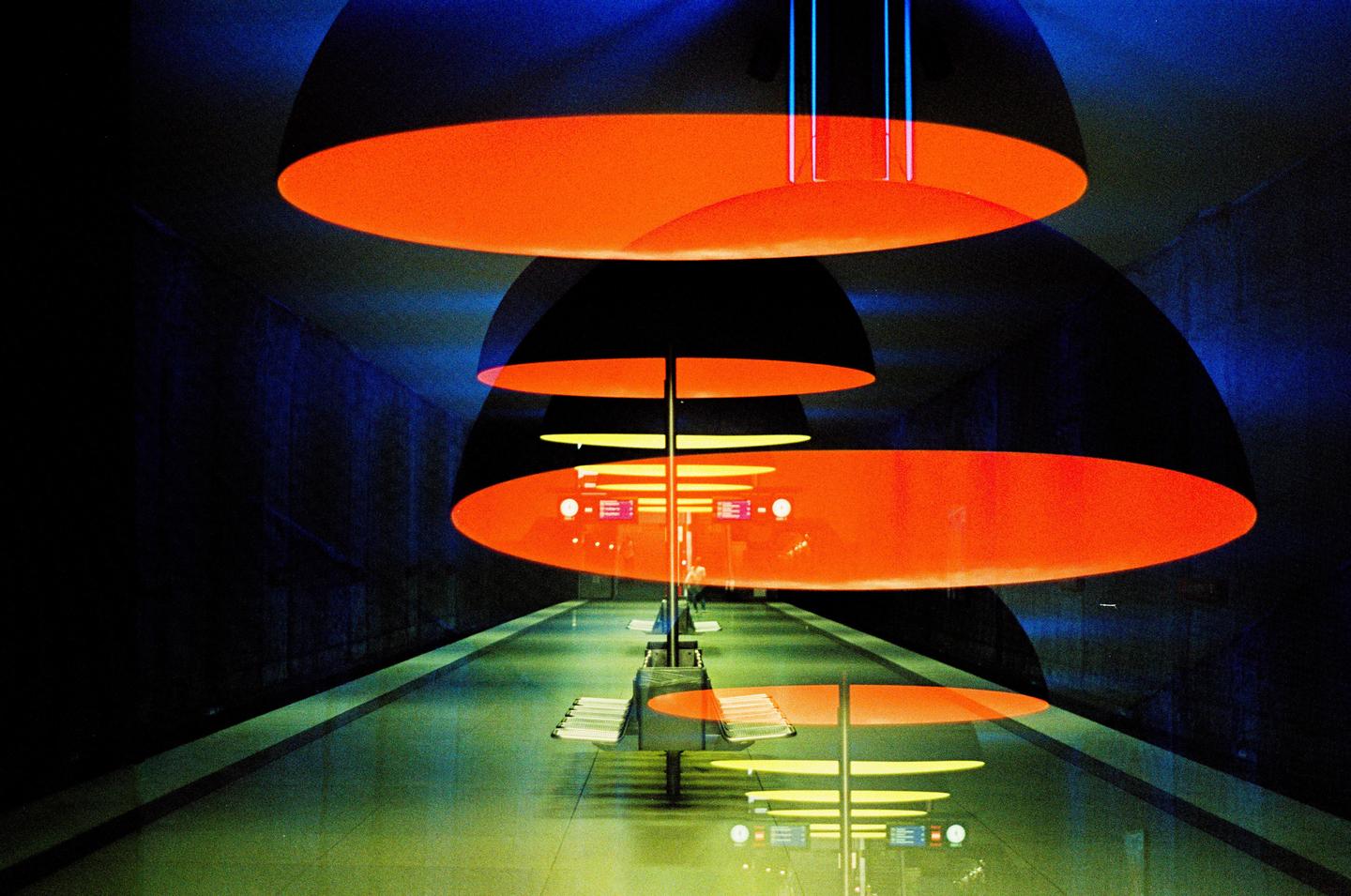 A double exposure shows a subway station with orange and blue lights.