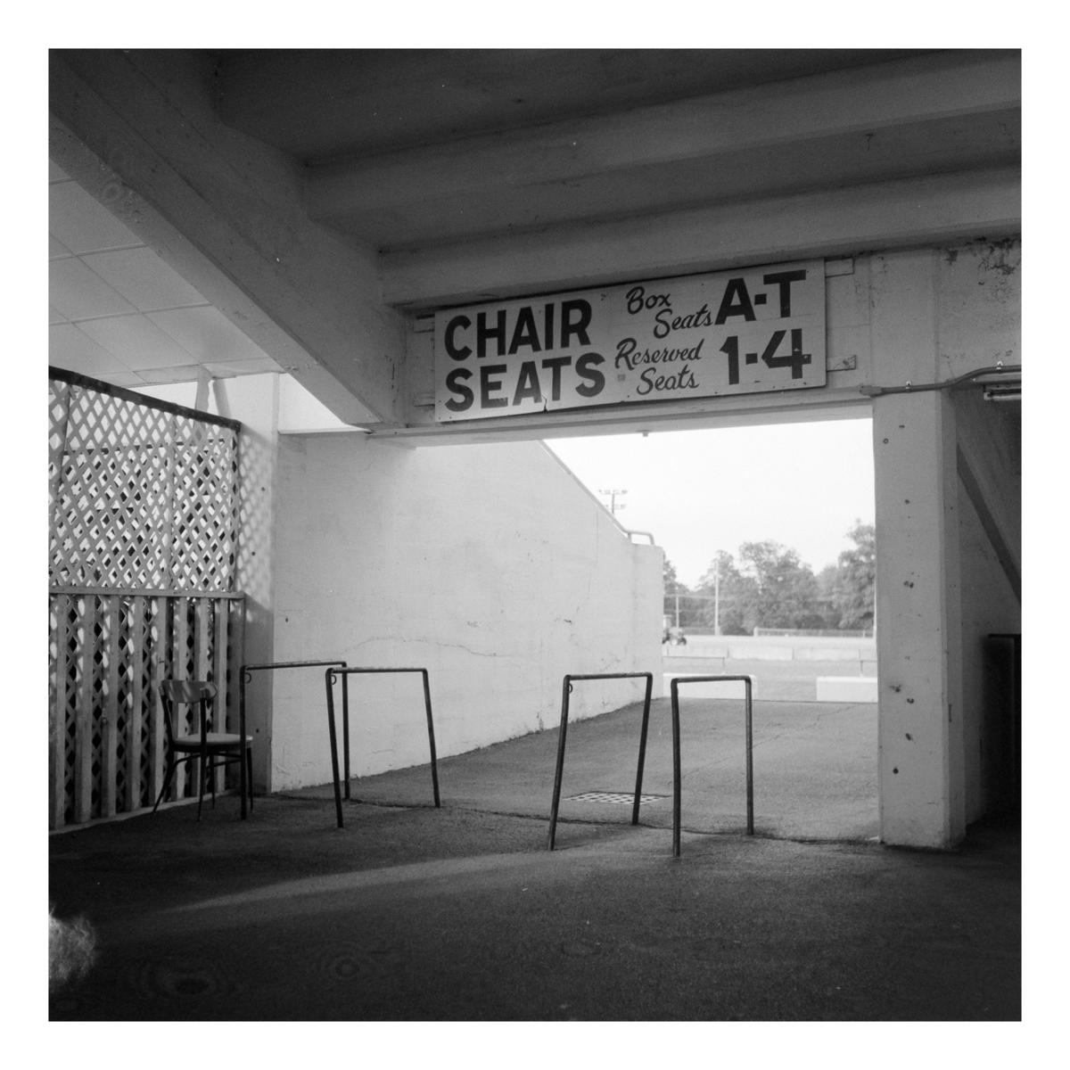 A sign for chair seats and box seats hangs above an entrance to a stadium.