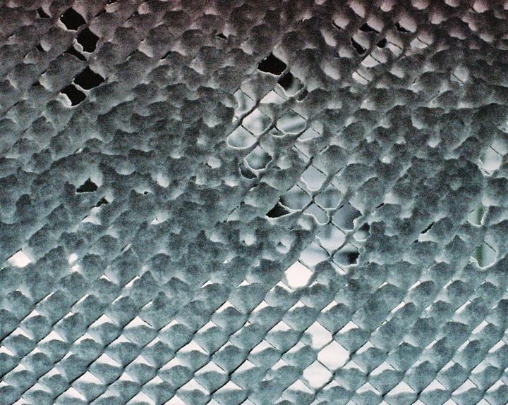 A chain link fence is covered in a fresh layer of snow.