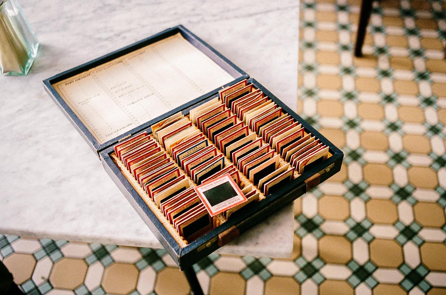 A box of slides sits on a marble table next to a patterned floor.