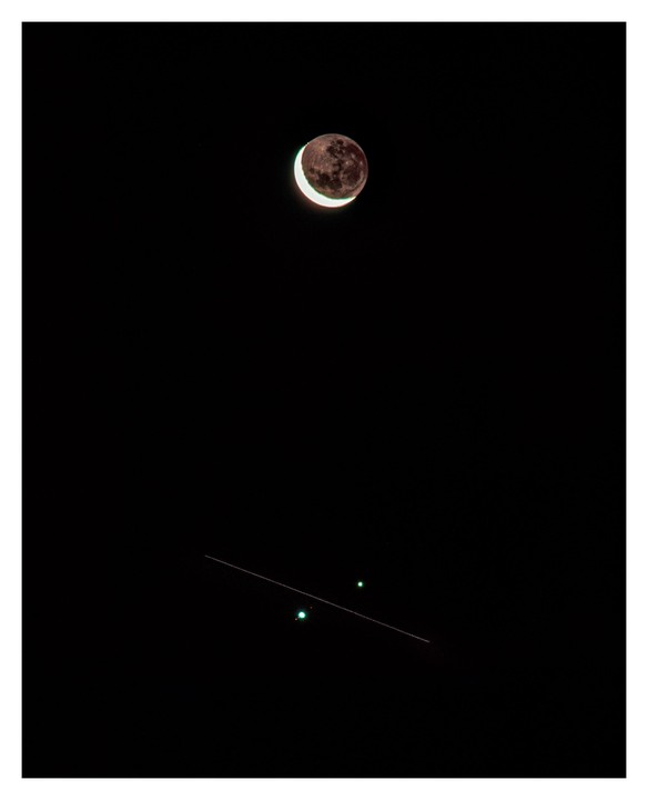 A crescent moon is visible in the night sky above a faint line and two green lights.