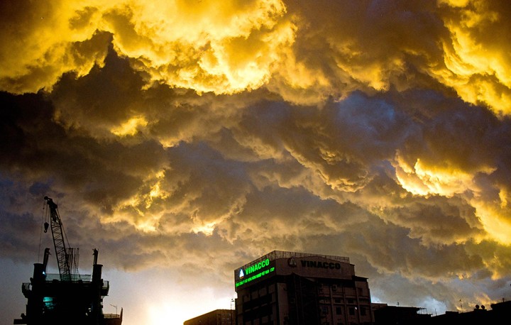A dramatic sky with golden clouds hangs over a city building and a construction crane.
