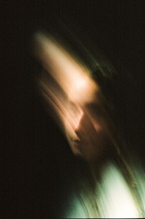 A blurry portrait of a woman with light on her face.