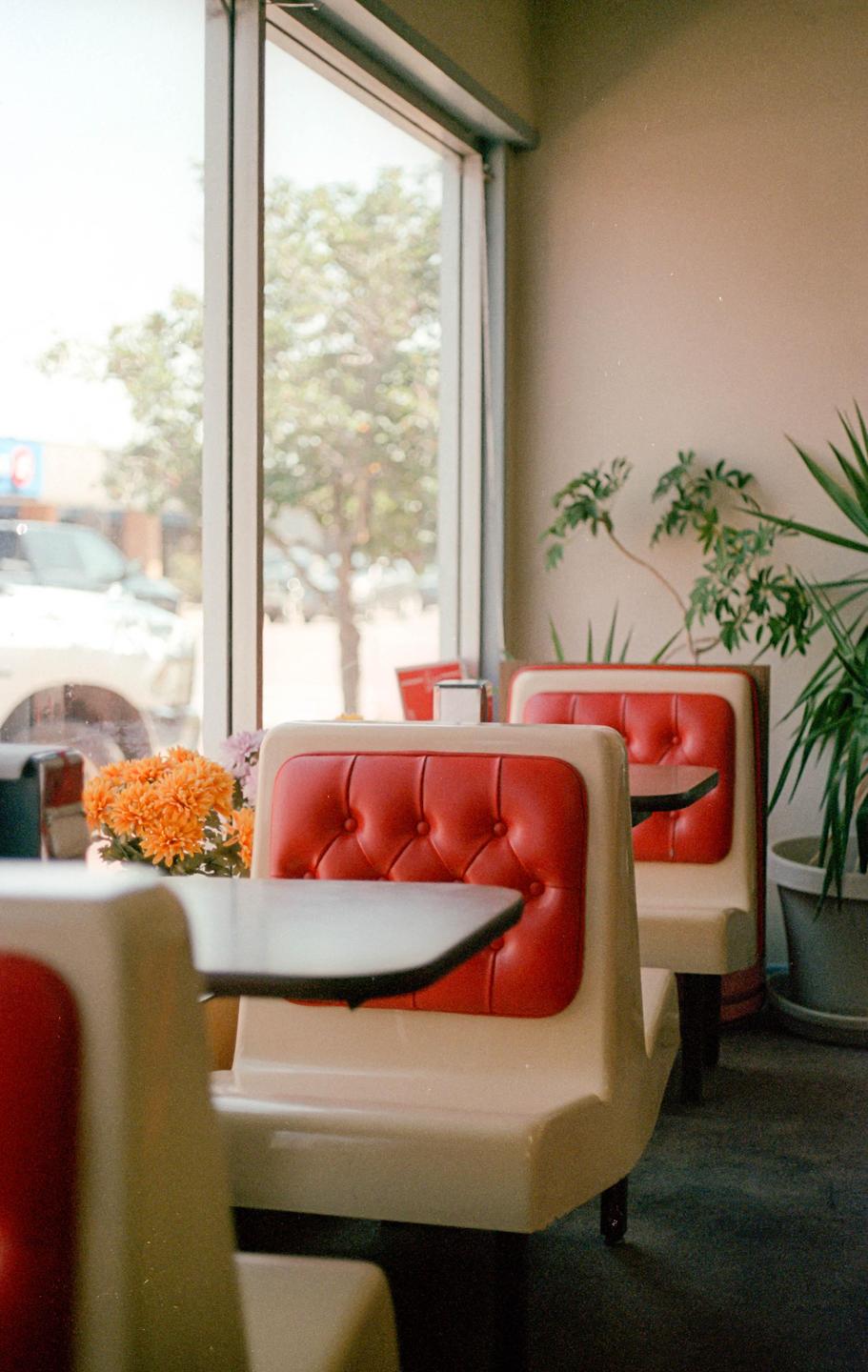 A diner interior with red booths and tables is visible next to a large window looking out onto a street.