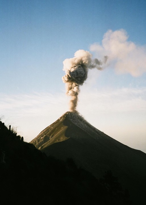 A volcano erupts, sending a large plume of smoke into the sky.