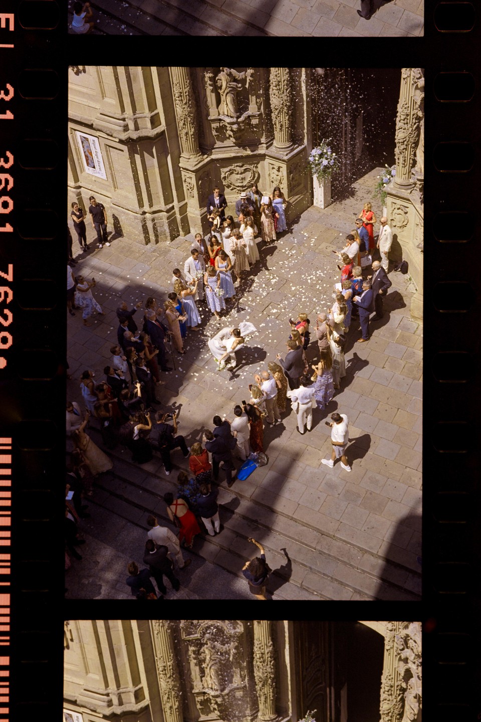 A wedding party stands outside a church as confetti falls on the bride and groom.