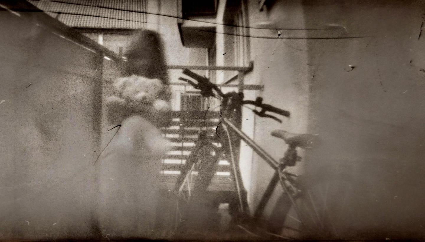 A blurry image shows a child holding a teddy bear next to a bicycle.