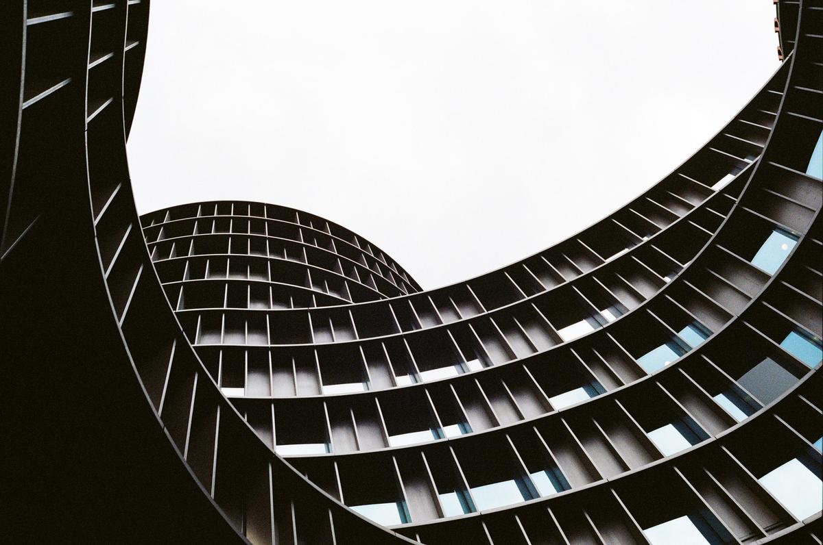 A low-angle view shows the curved facade of a modern building with many windows.