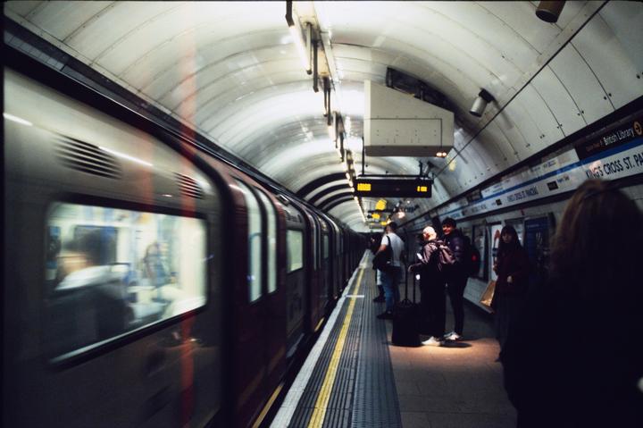 A train pulls into a subway station where people wait on the platform.