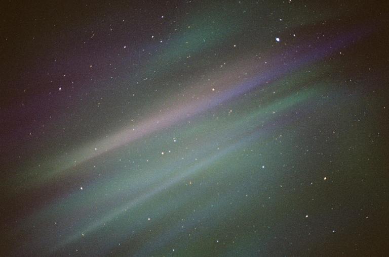 The night sky is filled with numerous stars and colorful bands of aurora borealis.
