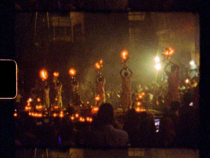 A crowd of people are gathered at night, with several individuals holding up illuminated objects.