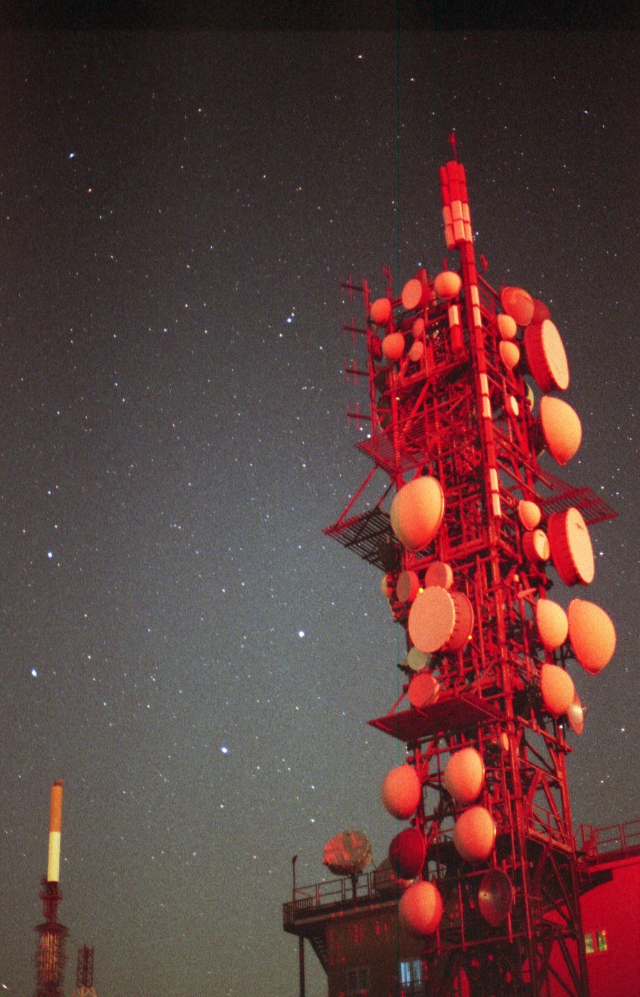 A red radio tower stands against a night sky filled with stars.
