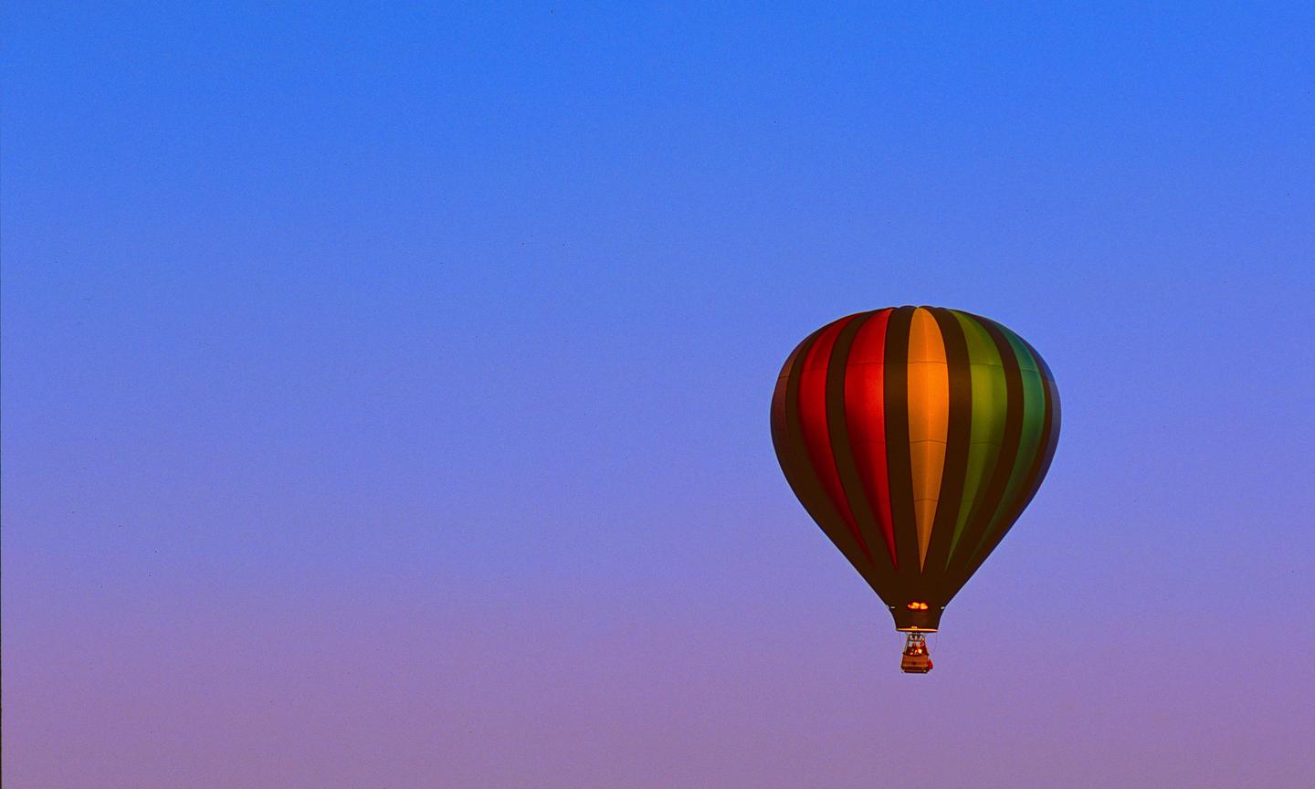 A colorful hot air balloon floats against a blue and purple sky.