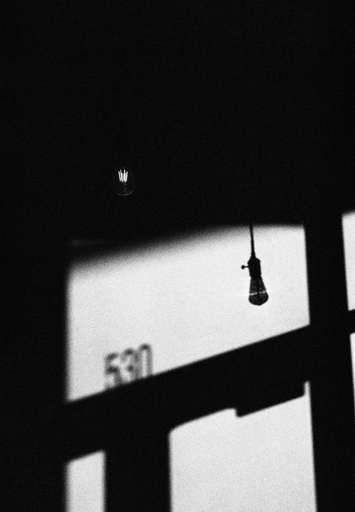 A lightbulb is visible in the upper left corner, with a shadow of a window frame and the number 530 cast on a wall.