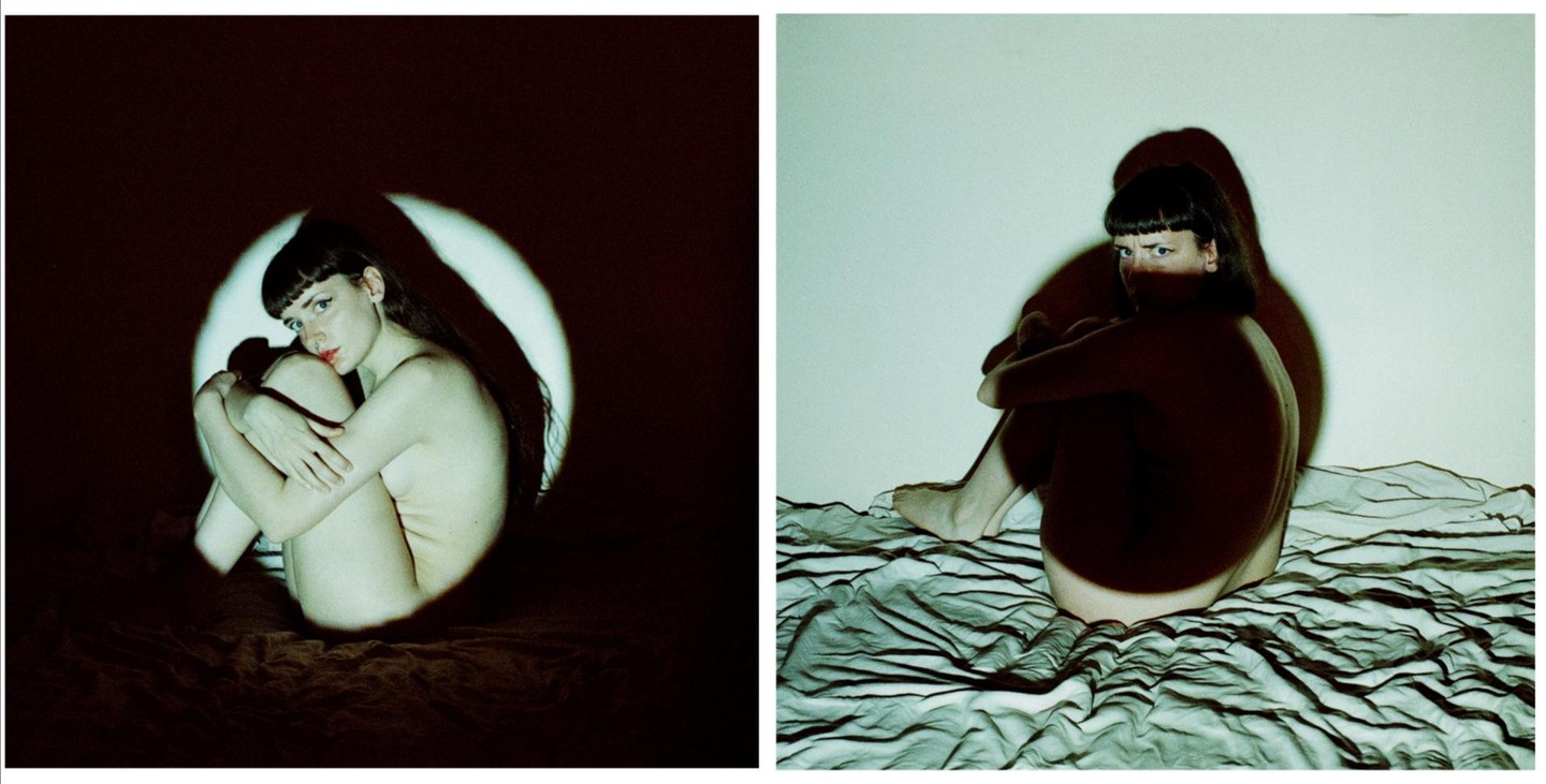 A woman sits on a bed in two self-portraits, one lit by a circular spotlight and the other by a green light.