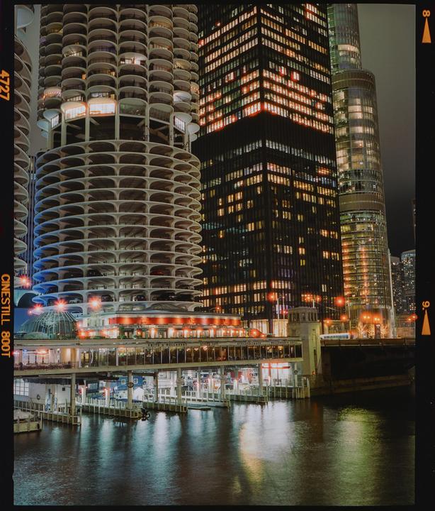 A river flows past several illuminated buildings in a city at night.