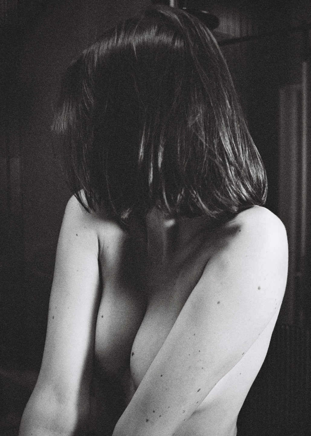 A woman with short hair is shown from the chest up, with her back to the viewer and her head turned to the side.