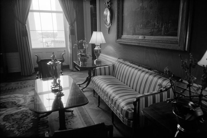 A striped sofa sits in a room with a large window and a painting on the wall.