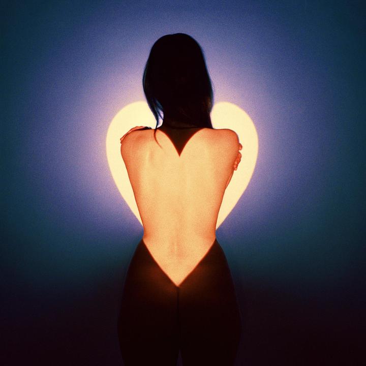A woman stands with her back to the viewer, illuminated by a heart-shaped light.