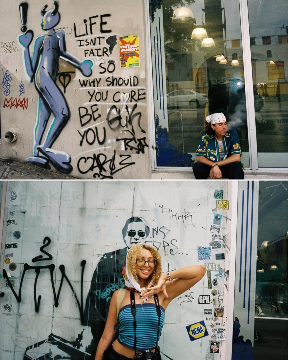 A man smokes a cigarette while sitting next to a wall with graffiti and a woman poses in front of a wall with graffiti.