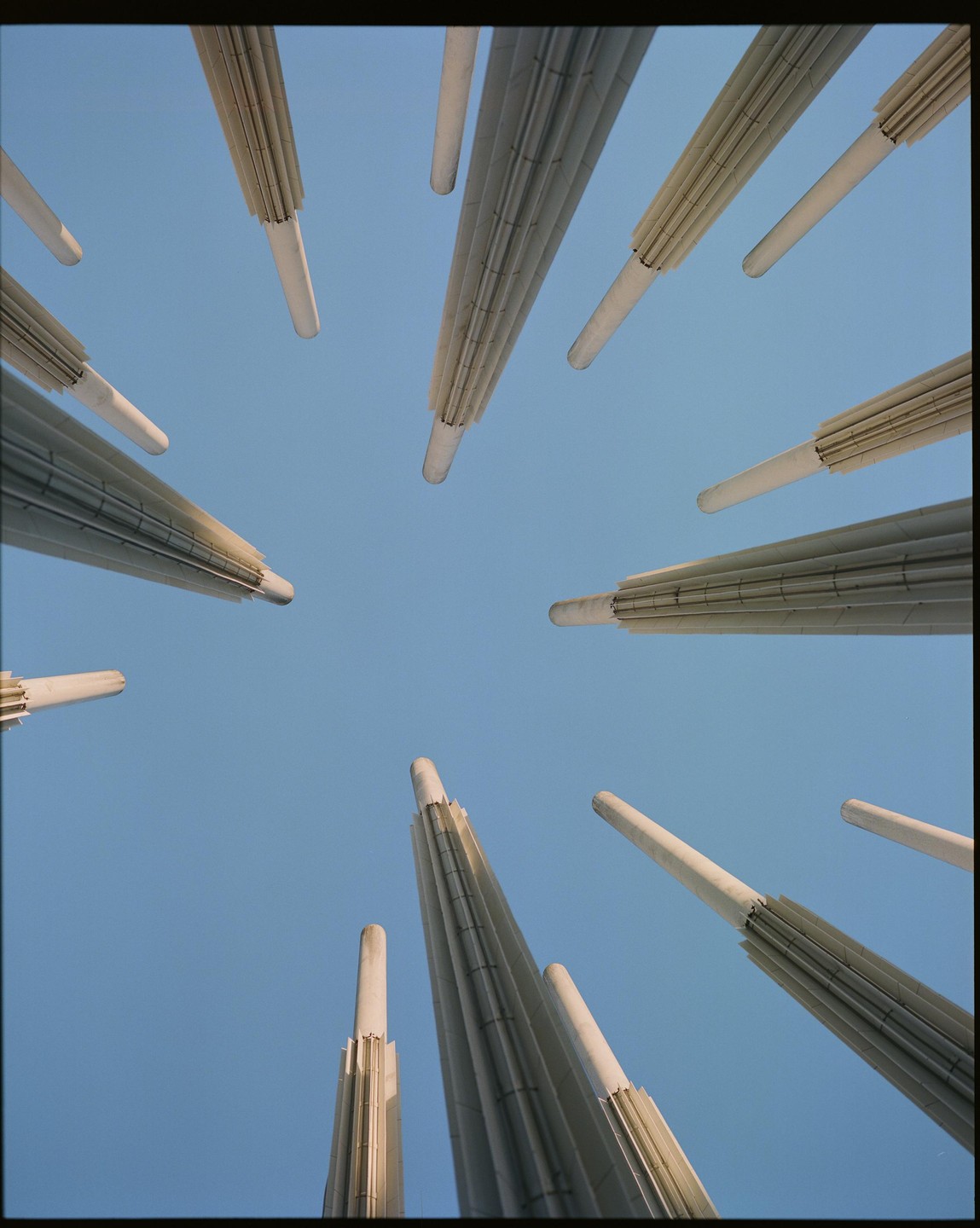 A low-angle view shows several tall, white, fluted pillars against a clear blue sky.