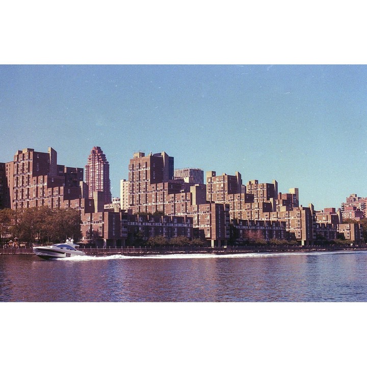 A boat moves across a body of water with a city skyline in the background.
