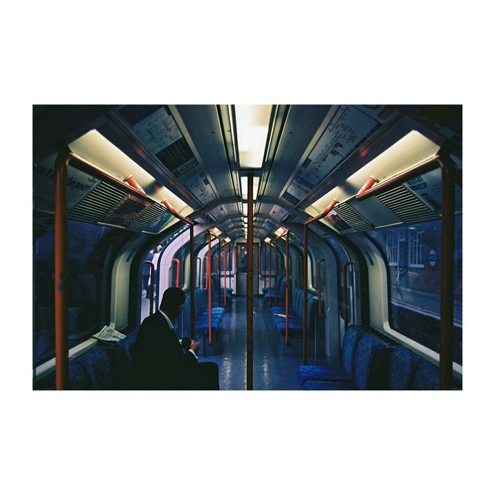 A man in a suit sits alone in a subway car at night.