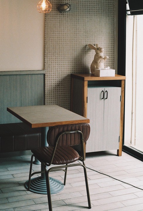 A cafe interior features a table, chair, and a rabbit figurine on a cabinet.