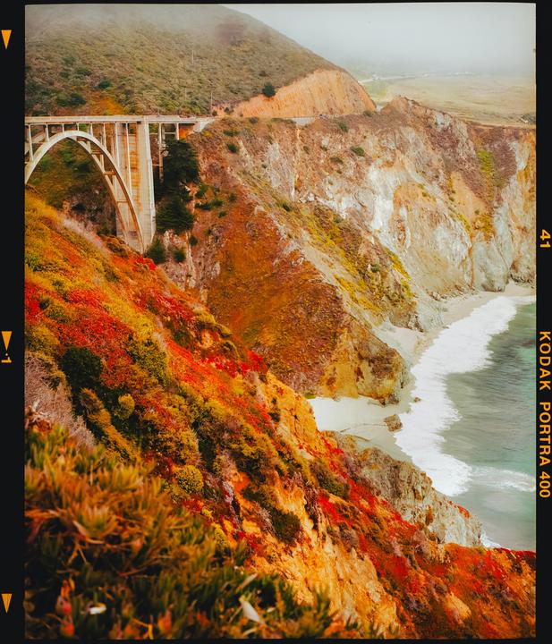 A bridge spans a canyon with a beach and ocean visible below.